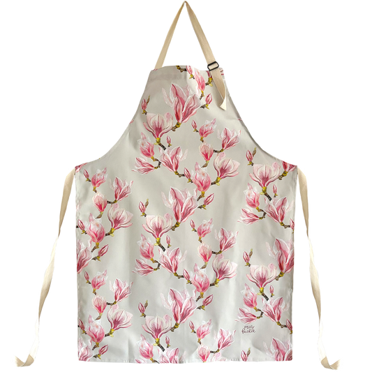 A cotton apron with hand painted magnolia blossom and buds design, predominantly in pink and green colors.