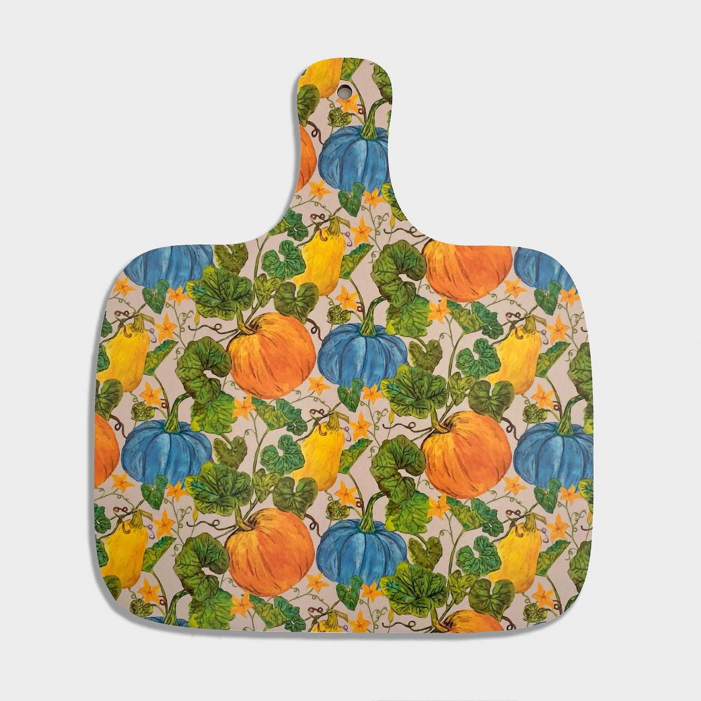 Medium chopping board with a colorful hand illustrated design featuring pumpkins, squash, leaves, and flowers on a light cream background.