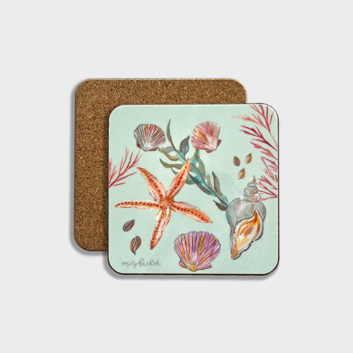 A square coaster with a light blue background featuring hand-painted coastal illustrations, including a starfish and shells. The coaster has a cork backing.