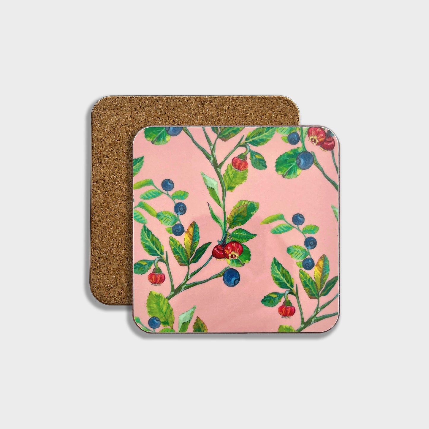 A square coaster with a floral pattern featuring bilberries and leaves on a pink background, with a cork backing.