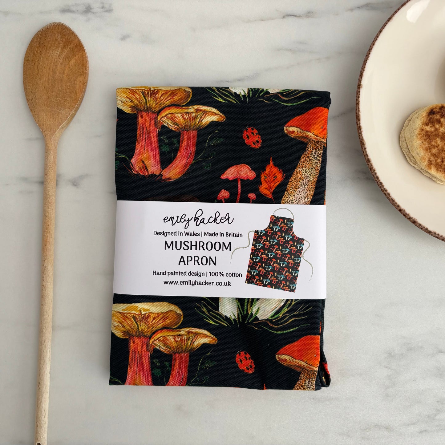 Folded colourful apron in paper belly band on marble worktop