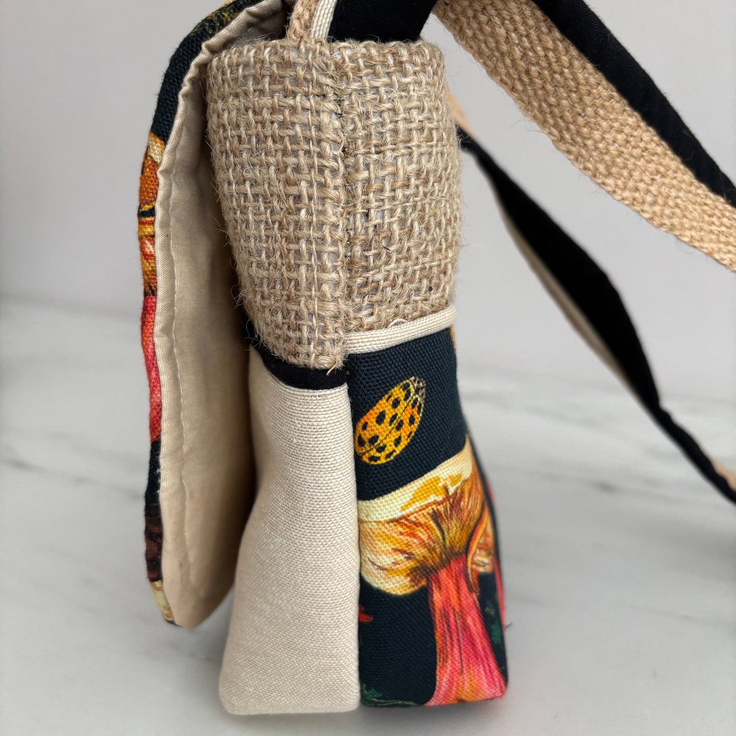 Handbag with mushroom pattern side view showing neutral colourway on a marble surface