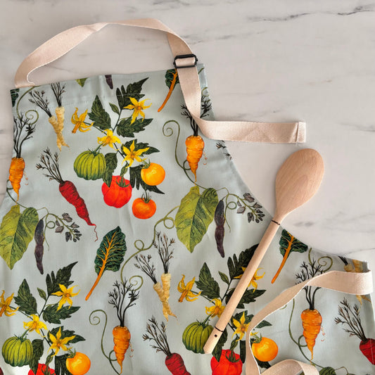 Apron with vegetable pattern and wooden spoon on a marble surface
