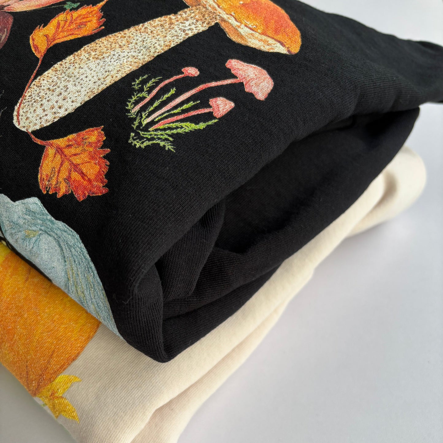 Two sweatshirts with autumn-themed designs photographed on a light white background.