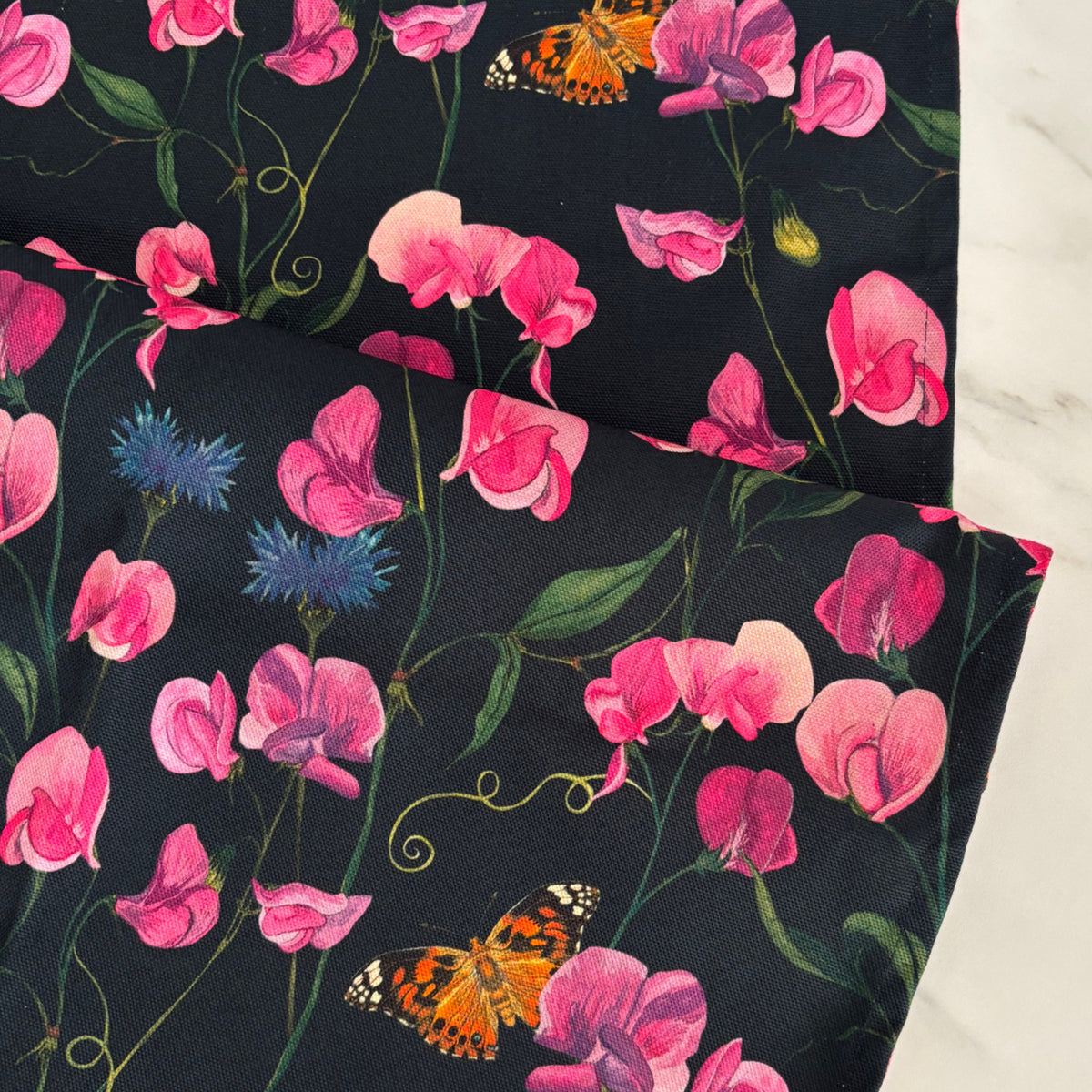 Table runner, hand painted sweet peas, cornflowers and painted lady butterfly design on a dark blue background.