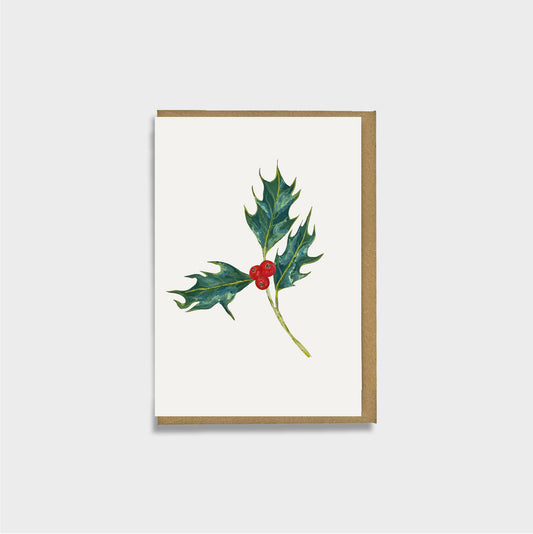 A mini Christmas card featuring a native holly and holly berries illustration on an off-white background, with a brown envelope, shown against a light gray backdrop.