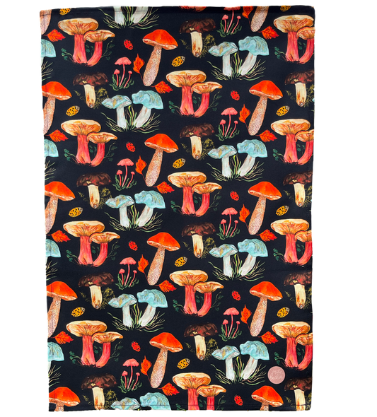 A cotton tea towel with hand painted illustrations of various mushrooms displayed across the fabric.