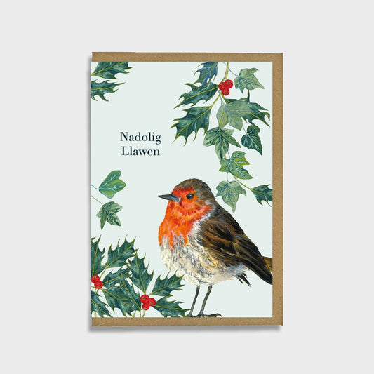 A christmas card featuring an illustration of a robin bird surrounded by green holly leaves and red berries on a pale background, with the text 'Nadolig Llawen' printed on the front.
