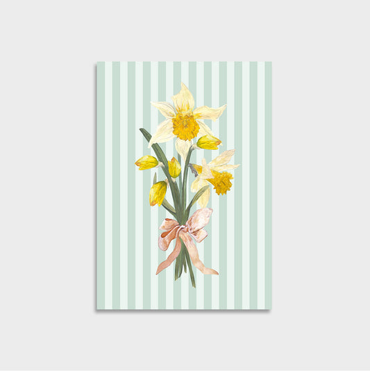 A6 art print or card featuring a bouquet of yellow daffodils tied with a pink ribbon, set against a mint green and white striped background, shown on a light gray wall.
