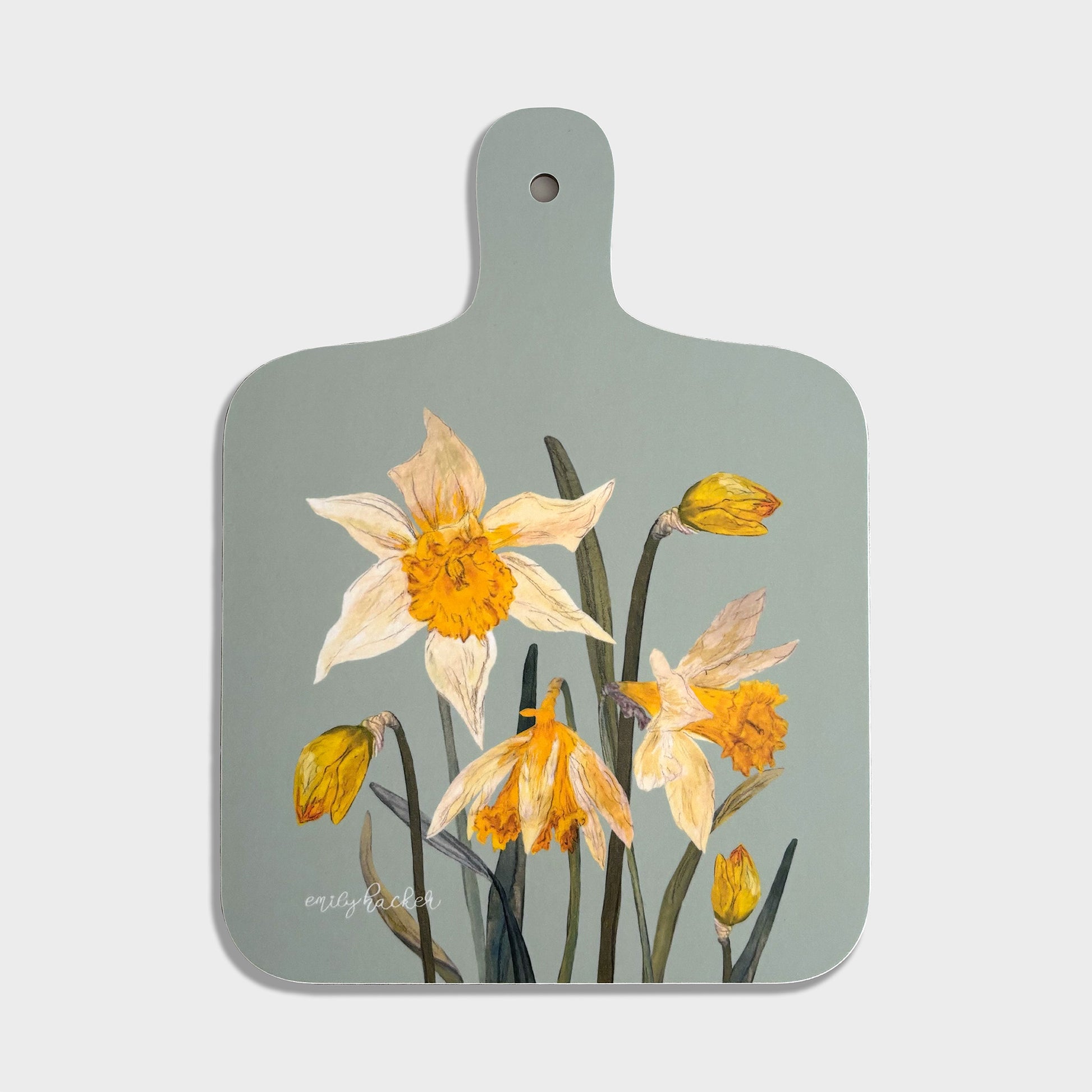 A small rectangular chopping board with a light green background and hand painted illustrations of wild daffodils in shades of yellow and orange.