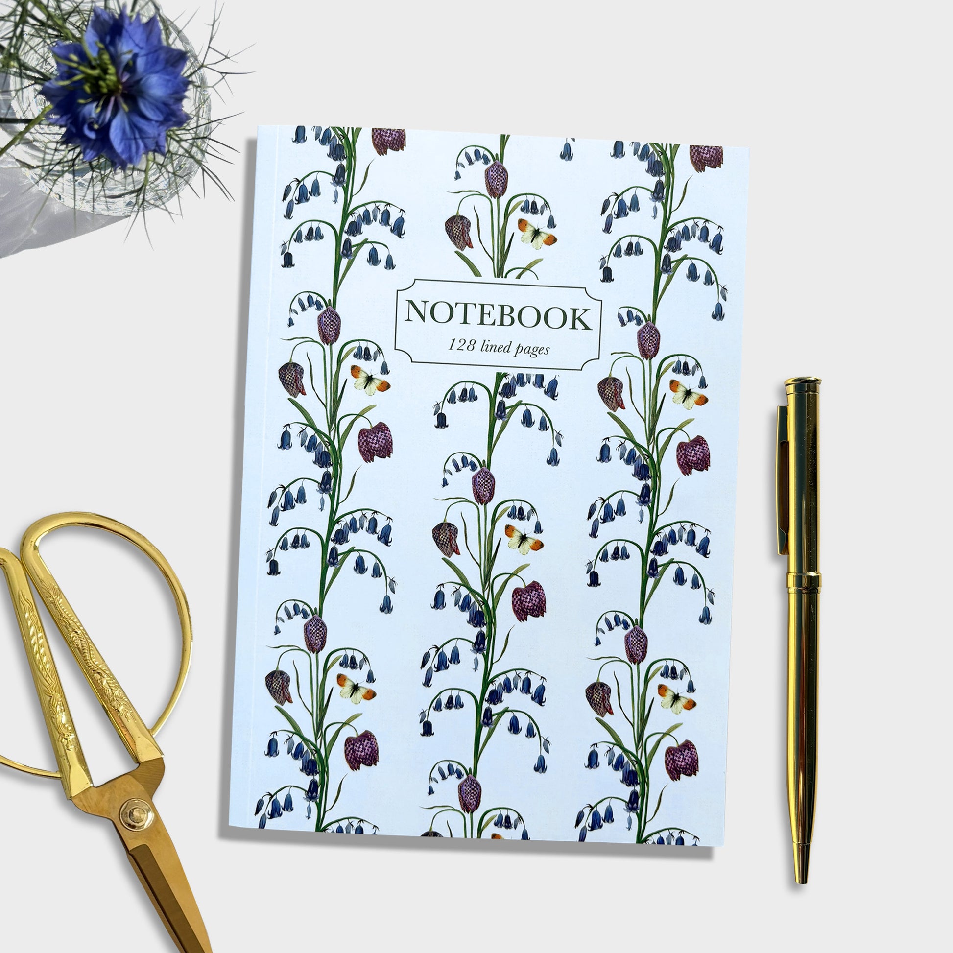 Native bluebell Notebook with hand illustrated floral design on cover, accompanied by gold scissors and pen on a white background