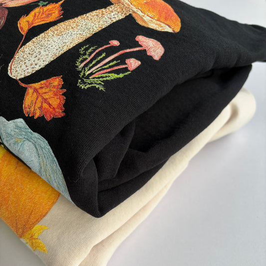 Two sweatshirts with autumn-themed designs photographed on a light white background.
