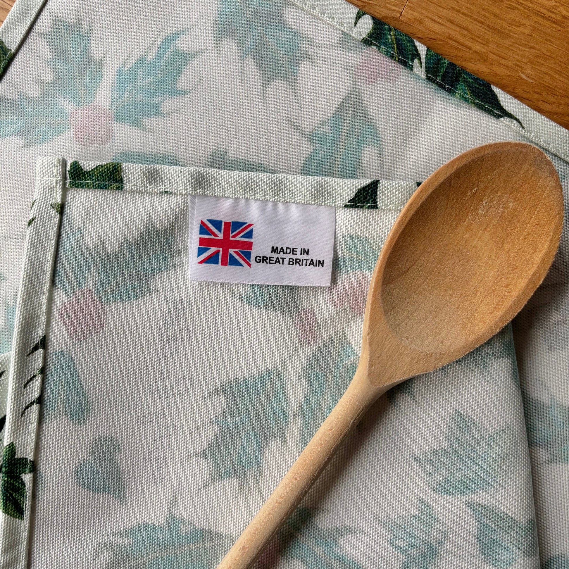 Christmas green and red patterned fabric with a wooden spoon and 'Made in Great Britain' label.