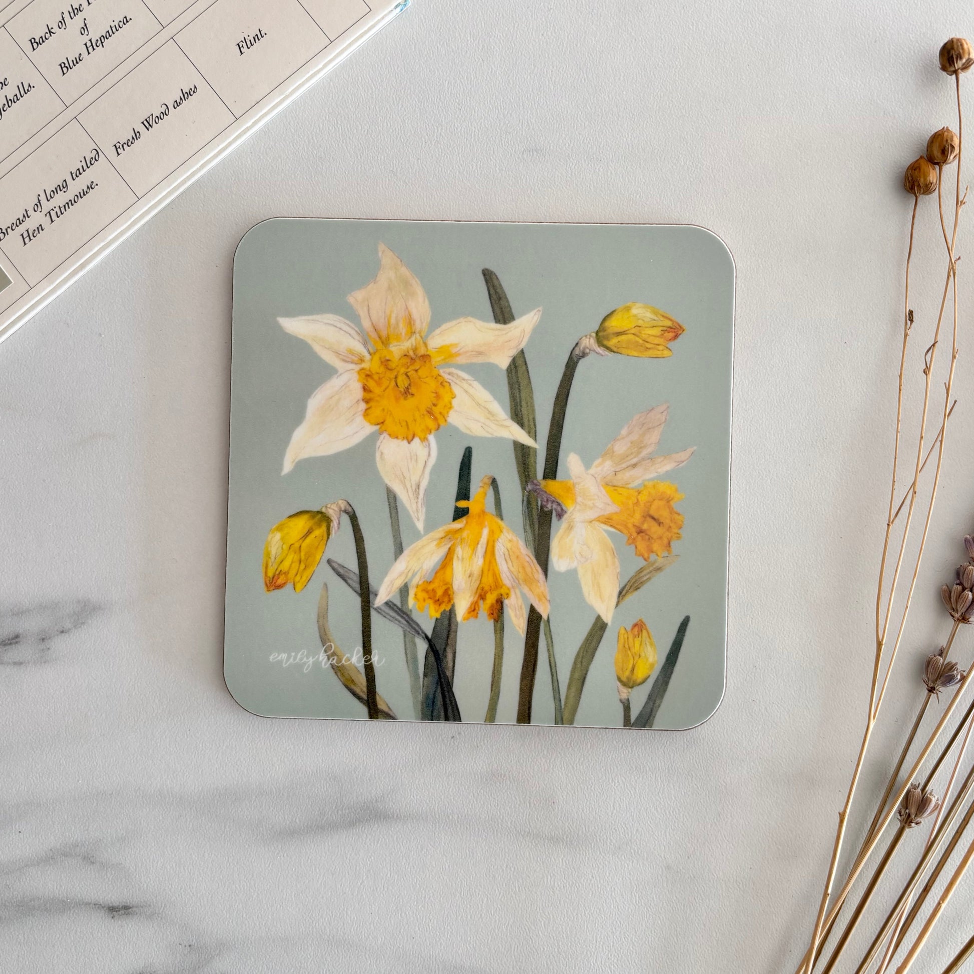 Melamine Coaster with hand illustated floral design on a marble surface with dried plants and a color swatch book.