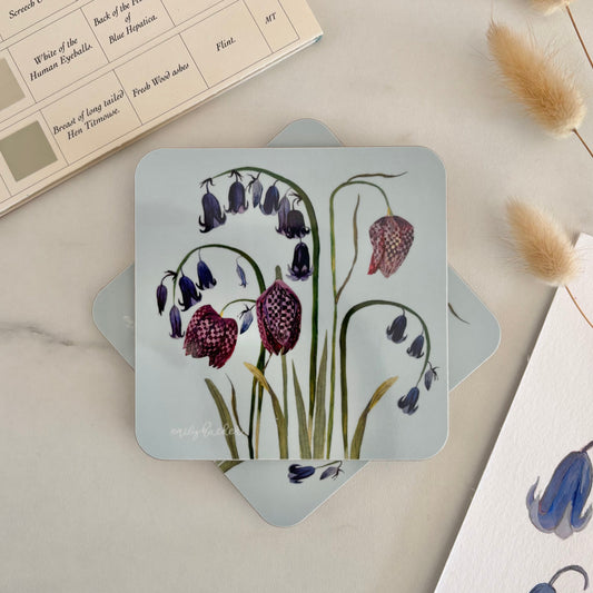 Floral blue Coaster with spring flower design on a marble surface and dried plants.