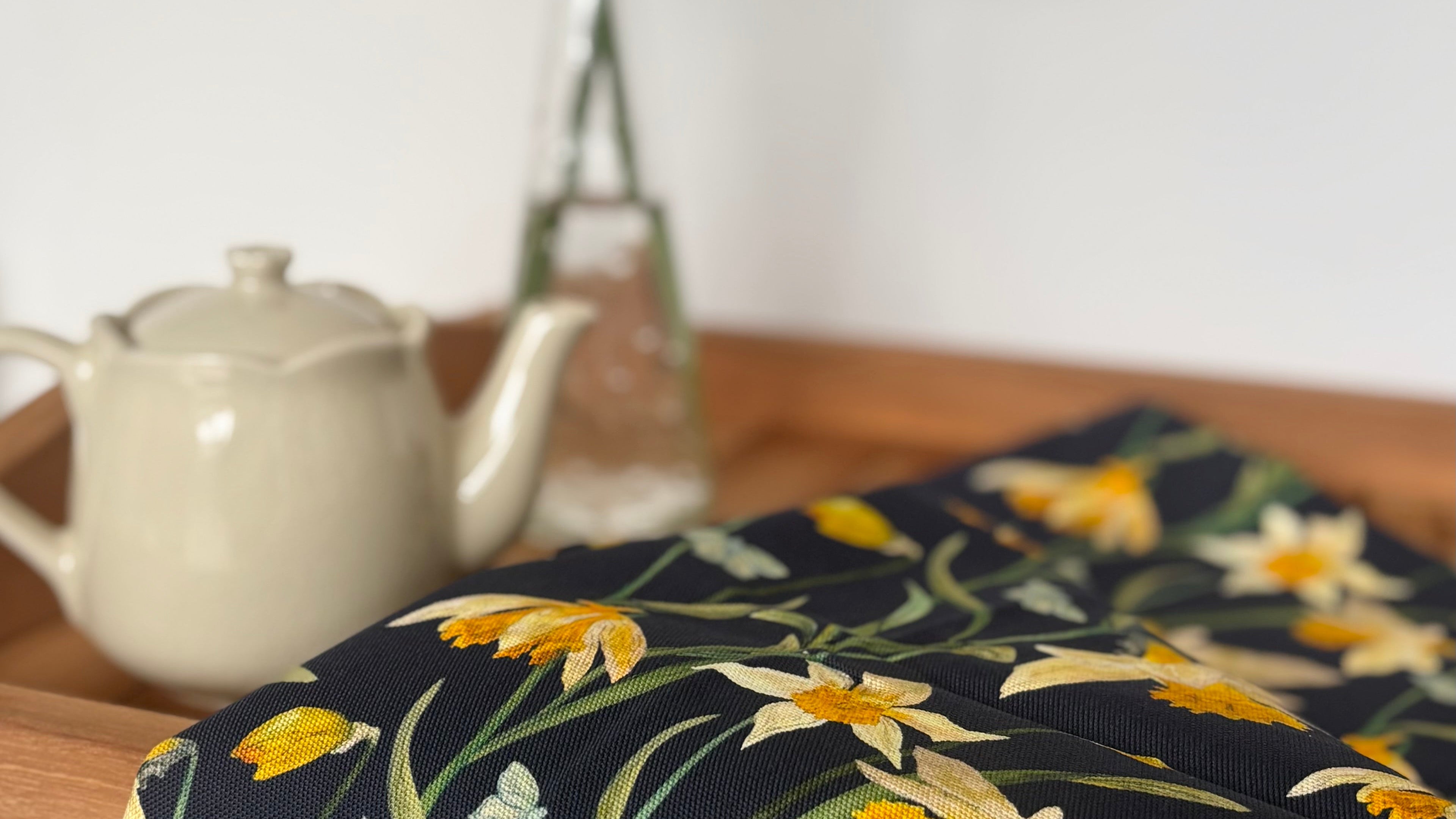 Floral-patterned tablecloth with yellow flowers on a wooden table.