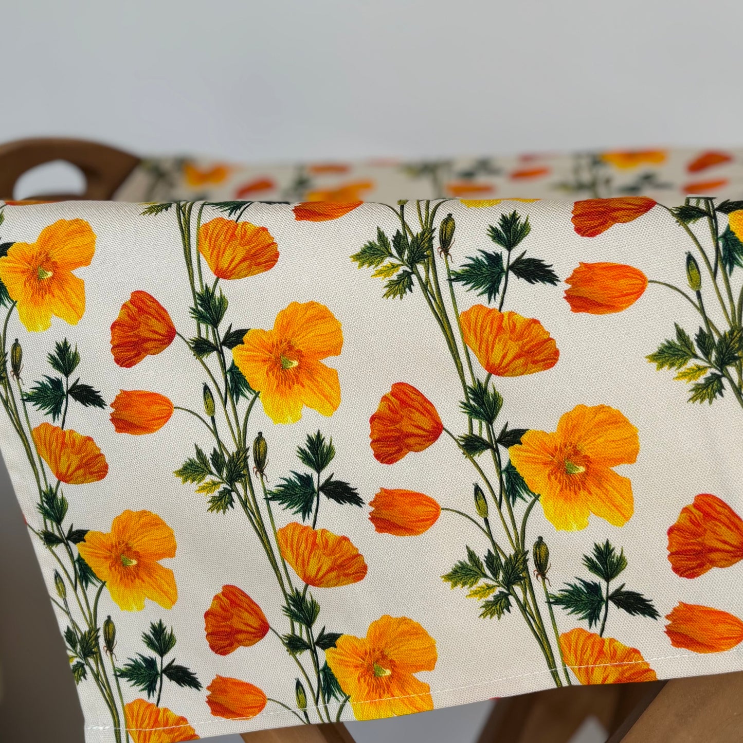 Pattered cotton tea towel featured hand painted illustrations of Welsh poppies in orange and yellow hues