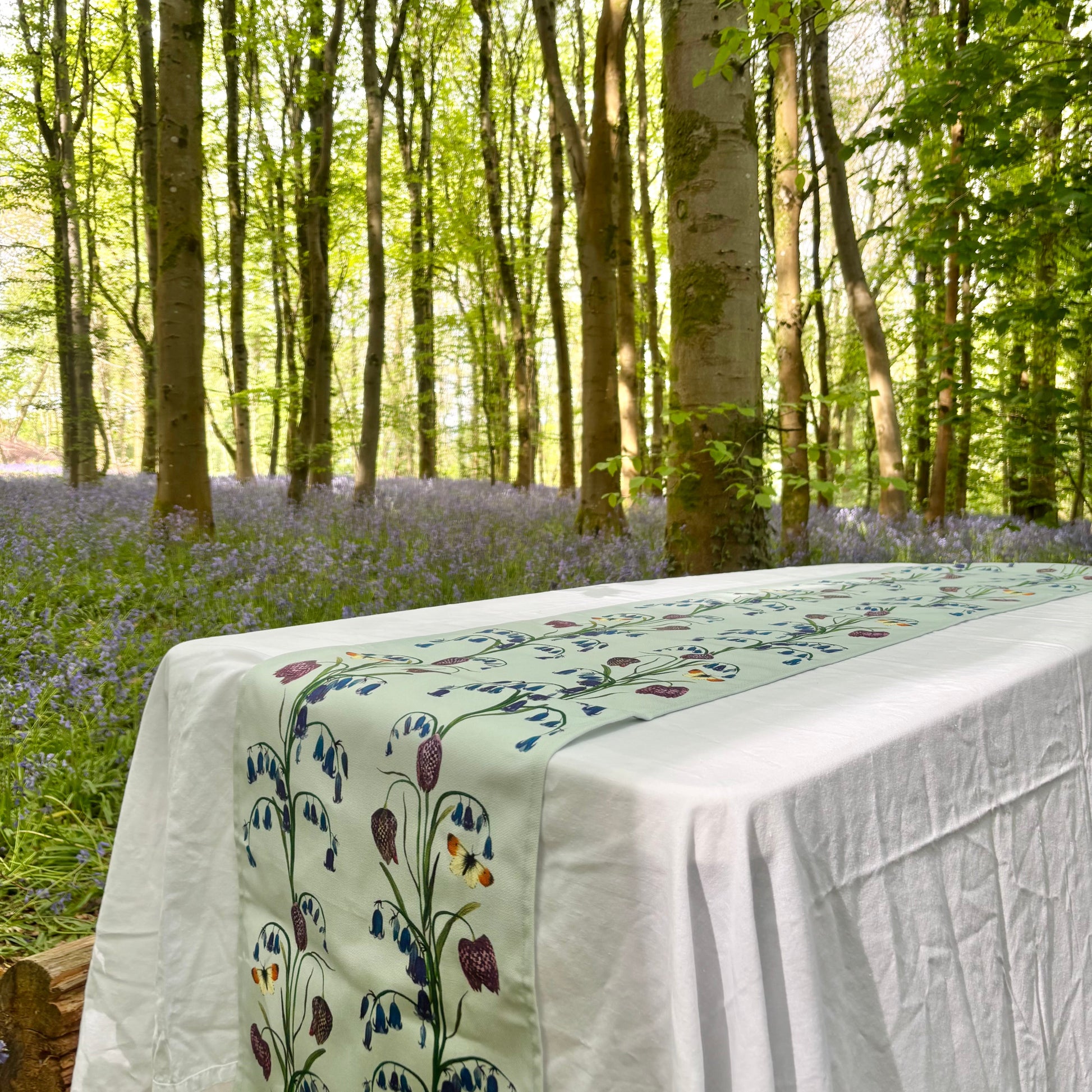 Tablecloth with floral bluebell and snake head fritillary design in a forest setting