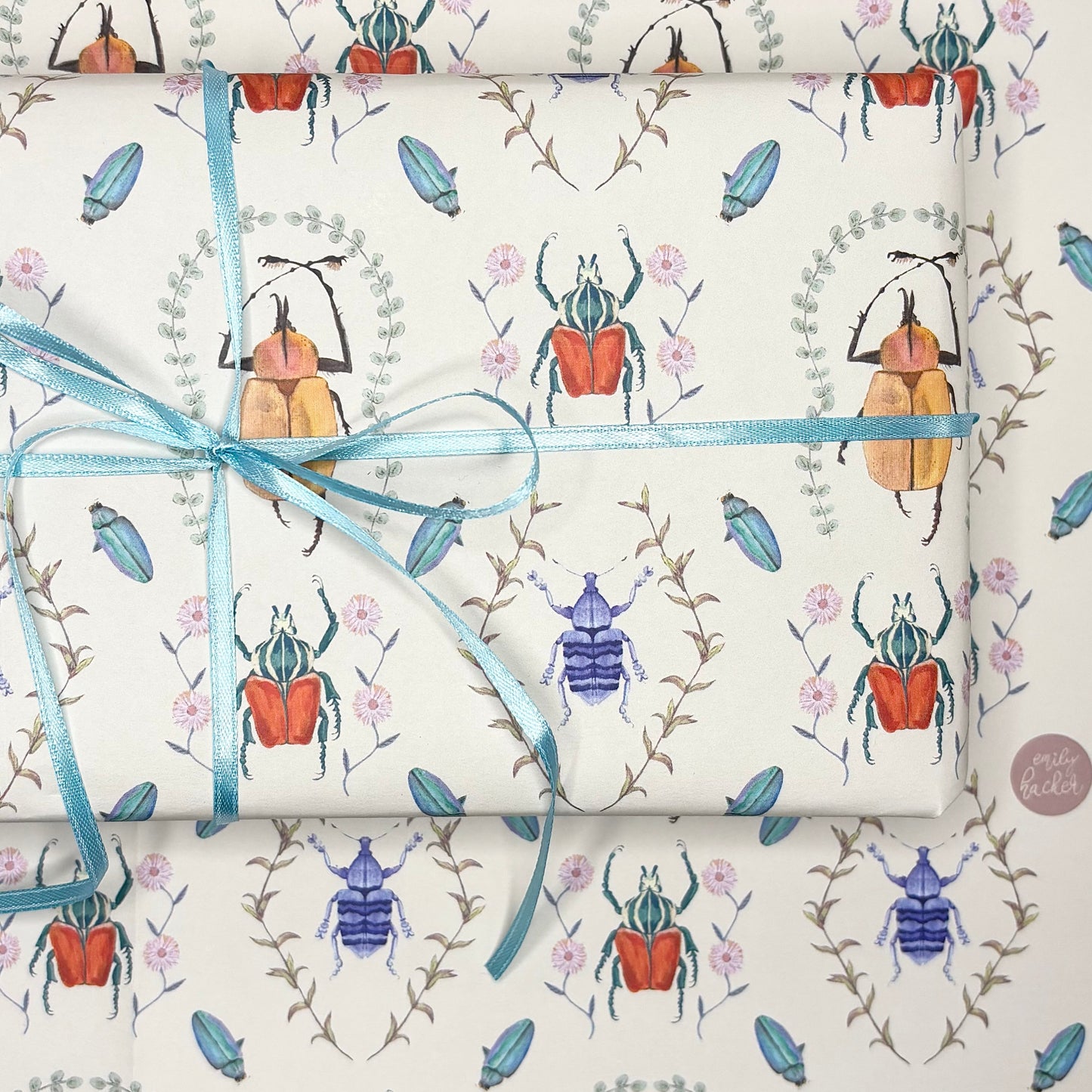 Roll of hand illustrated beetle wrapping paper with beetle pattern and blue ribbon 