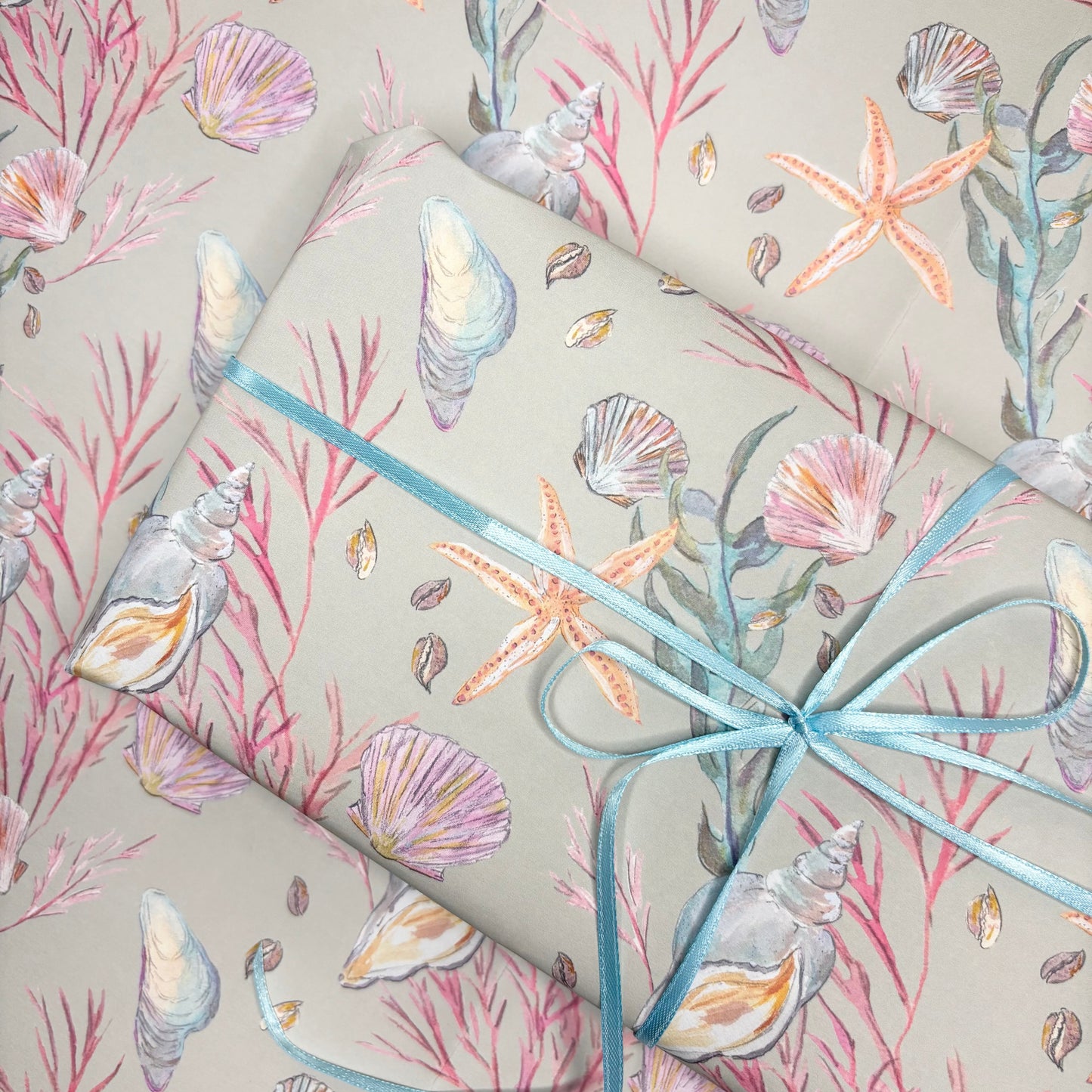 Gift wrap in seashell and starfish patterned paper with blue ribbon.