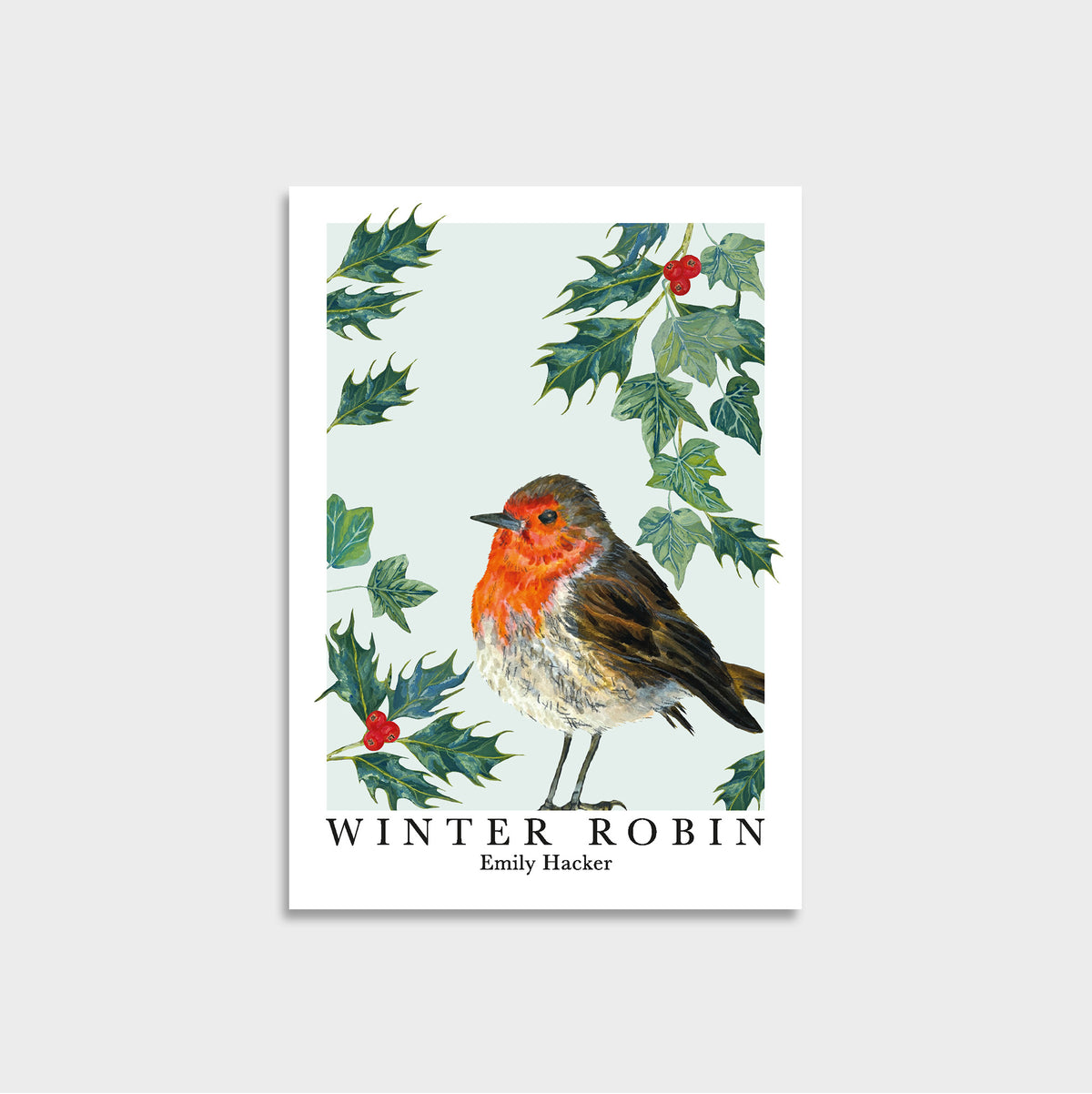 A print  featuring a winter robin illustration with holly leaves and red berries, shown on a light blue background. The print reads 'WINTER ROBIN' and 'Emily Hacker'.