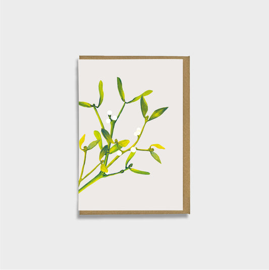 A mini card featuring mistletoe foliage illustration on an off-white background, with a  brown envelope, shown against a light gray backdrop.
