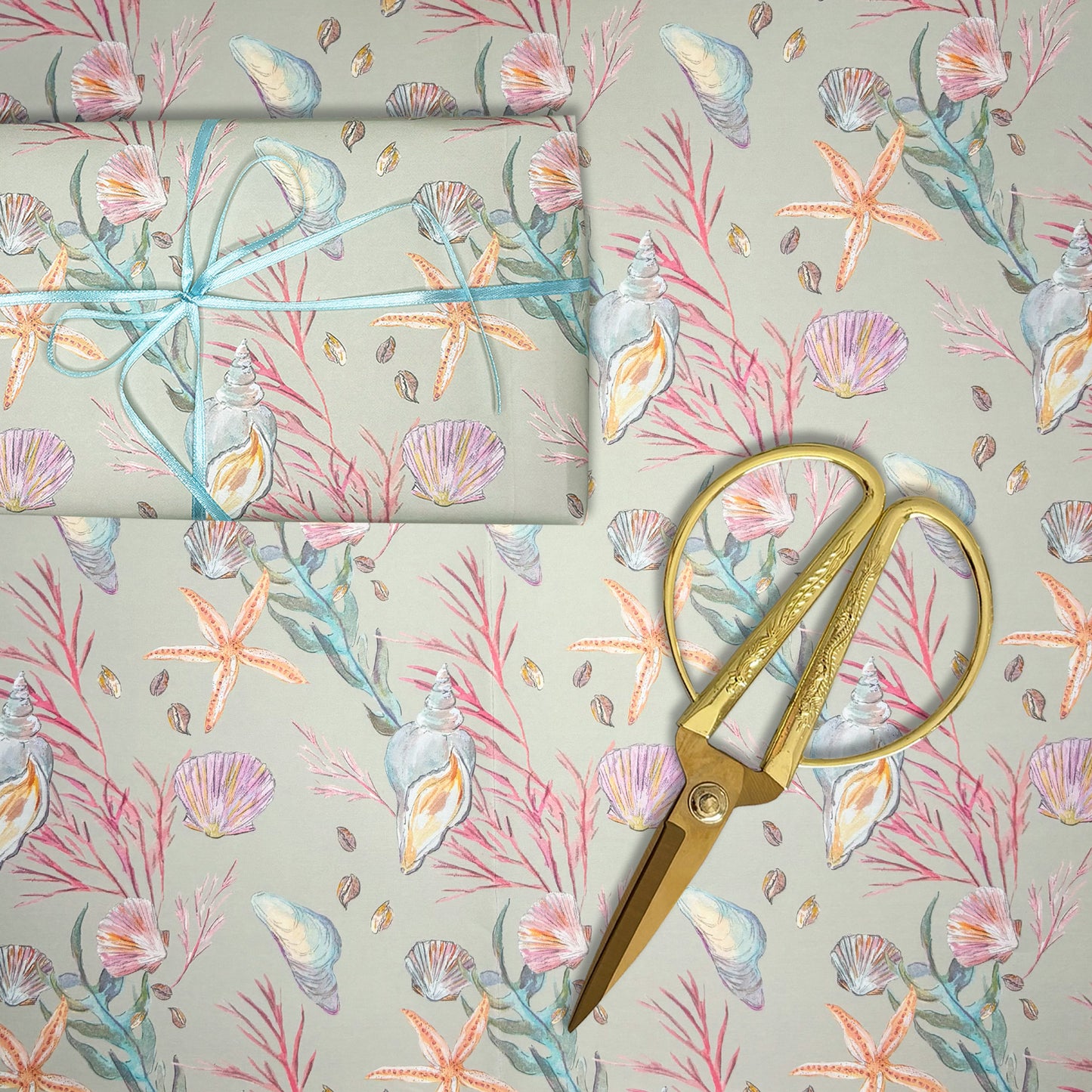 Seashell and starfish hand illustrated wrapping paper with gold scissors on a matching background