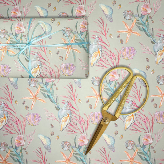 Seashell and starfish hand illustrated wrapping paper with gold scissors on a matching background