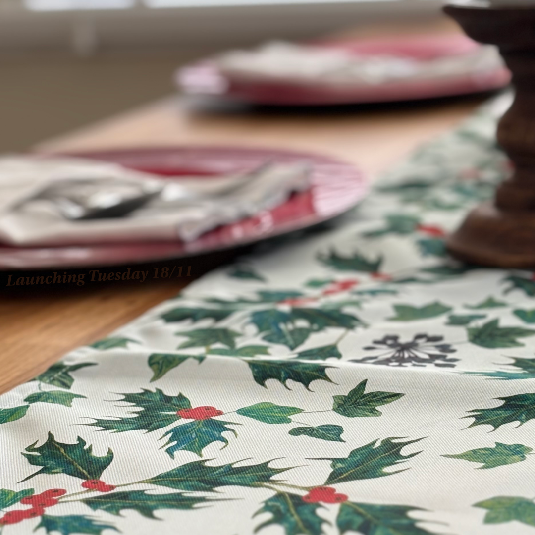 Christmas Table setting with a holly and ivy leaf patterned tablecloth.