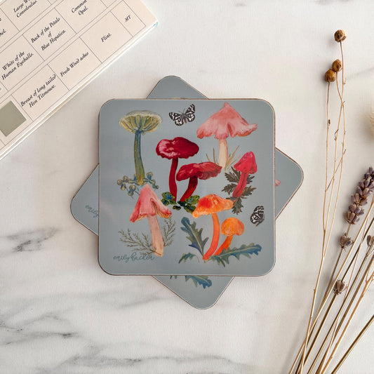 Waxcap mushroom themed hand illustrated coasters on a marble surface with dried plants.