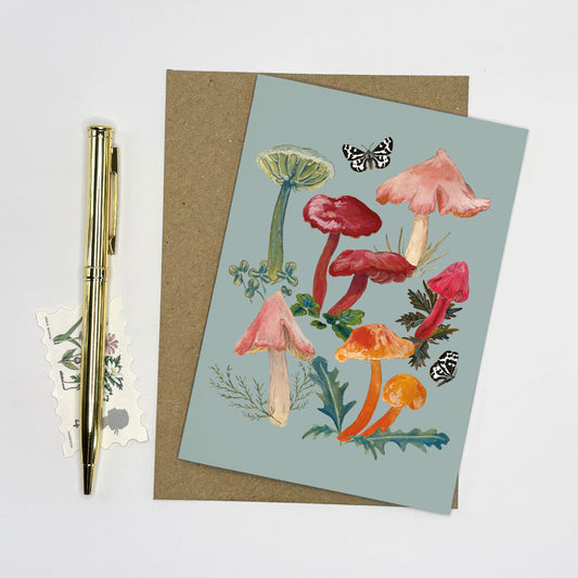 Mushroom Greeting card with rare waxcap vibrant mushroom hand painted illustrations on a light blue background, accompanied by a pen and postcard.