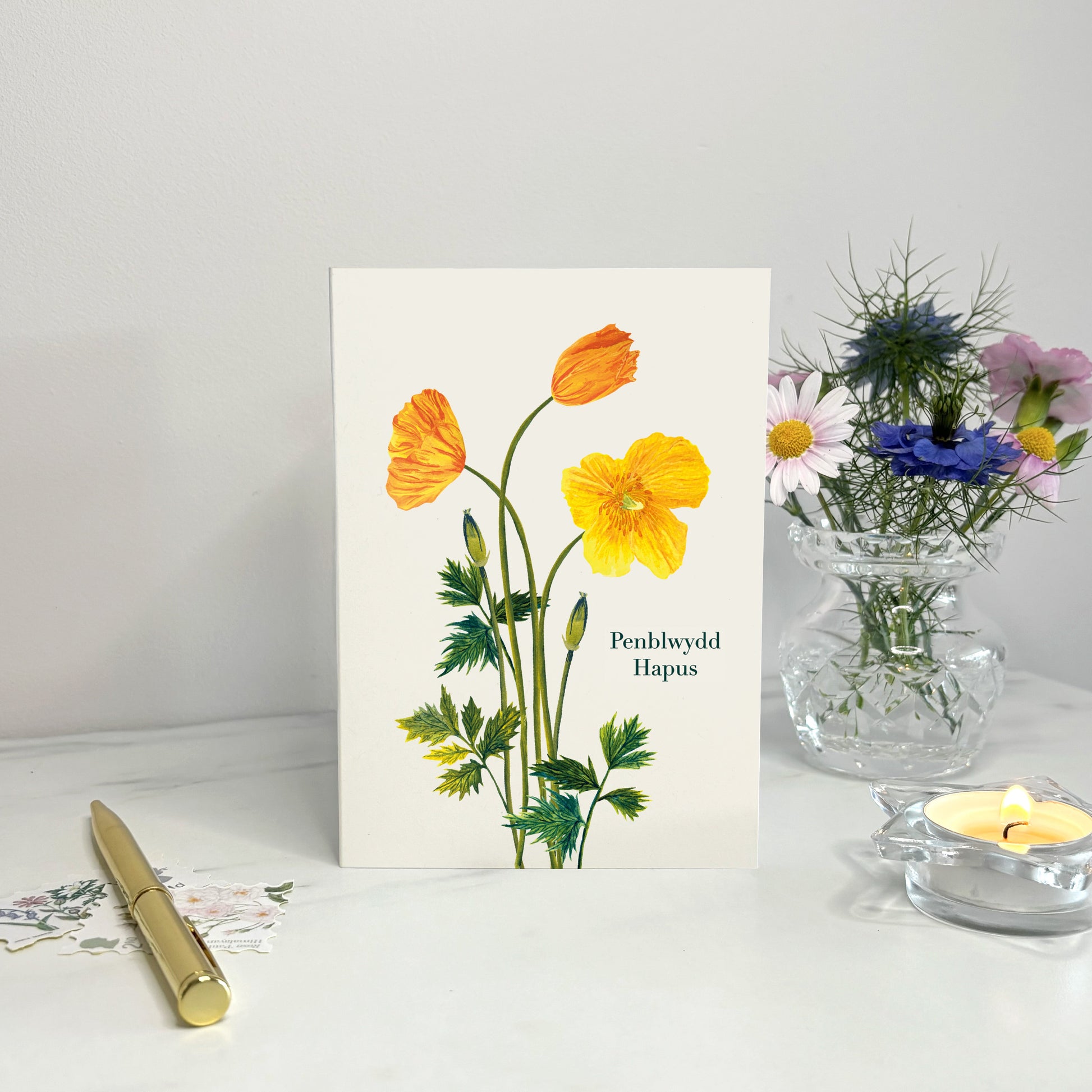 British wildflower Eco Greeting card with floral Welsh poppy design on a white surface with a candle and vase