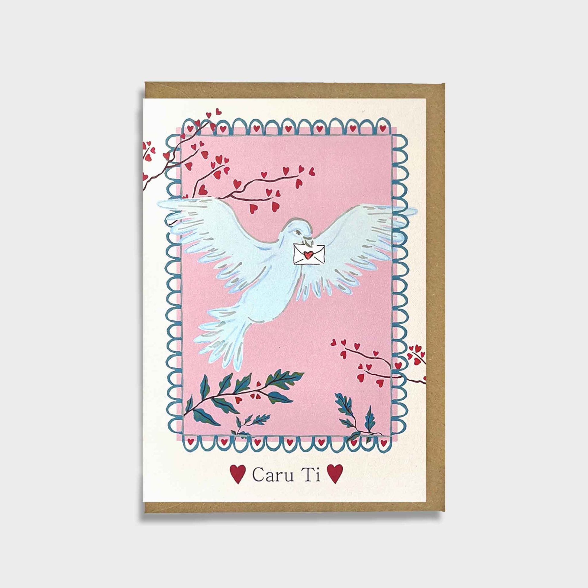 Greeting card with a dove with Welsh for love you Caru ti  holding an envelope on a pink background